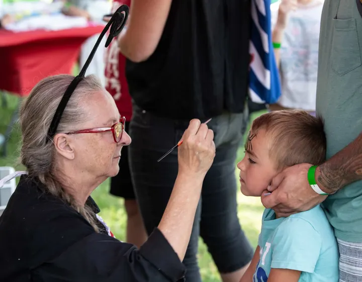 A child and an older festival guest sharing a relaxed moment in 2025